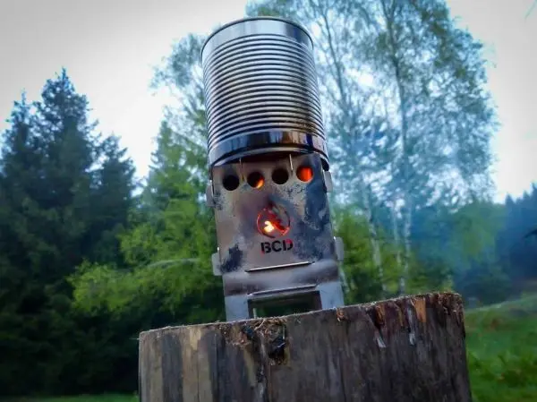 Hobo-Kocher mit Flamme auf einem Holzstück in der Natur