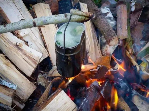 Kessel hängt über offener Flamme auf Holzscheiten