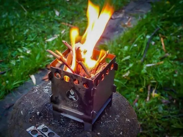 Kleine Flamme brennt in einem Metallkocher mit Holzstücken