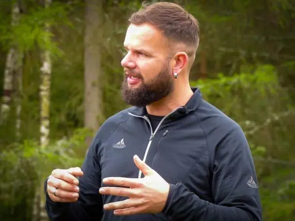 Mann erklärt etwas mit gestikulierenden Händen im Wald