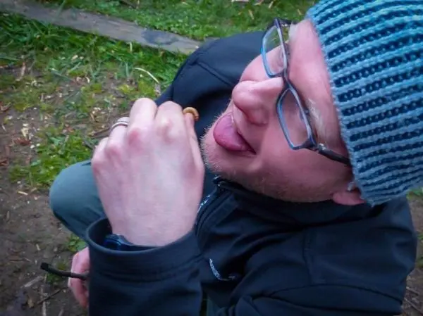 Mann hält einen kleinen Gegenstand mit der Hand und leckt daran