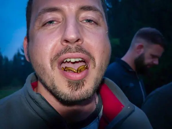 Mann mit Raupe im Mund, im Hintergrund verschwommene Personen