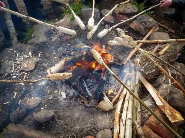 Mehrere Stöcke mit Teig über einem Feuer geröstet beim Survival Training
