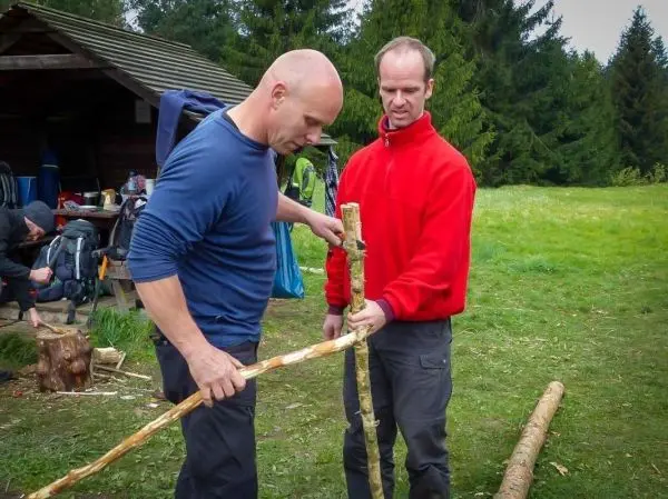 Zwei Personen arbeiten gemeinsam an einer Holzverbindung mit einem Stock