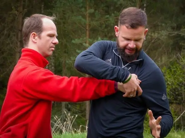 Zwei Personen üben eine Selbstverteidigungstechnik im Freien