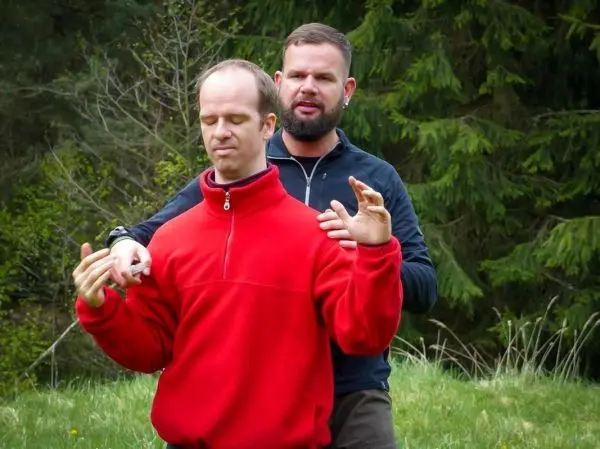 Zwei Personen üben eine Technik im Freien, einer steht hinter dem anderen