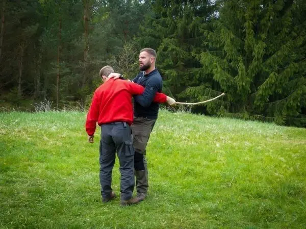 Zwei Personen üben eine Technik mit einem langen Stock im Freien