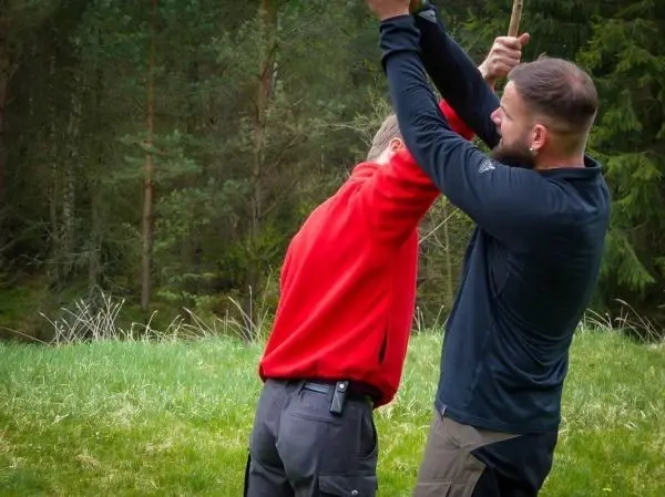 Zwei Personen üben eine Technik mit einem Stock im Freien