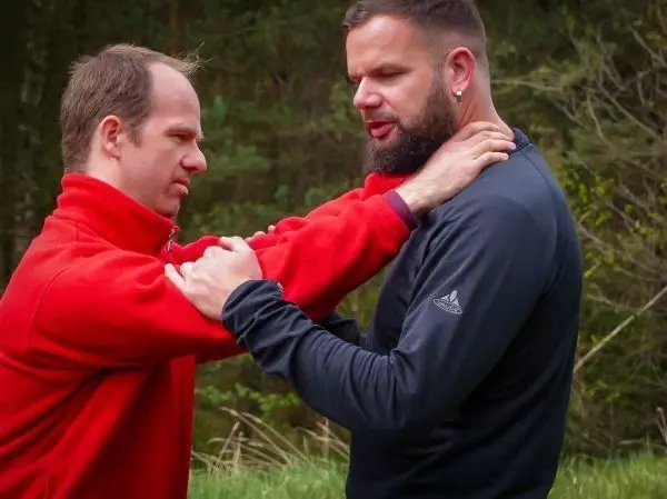 Zwei Personen üben eine Technik zur Kontrolle des Gegners im Freien