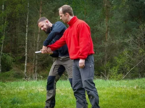 Zwei Personen üben eine Technik zur Kontrolle eines Arms im Freien