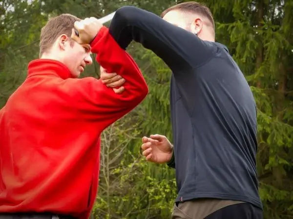 Zwei Personen üben einen Nahkampf mit einem Messer in der Natur