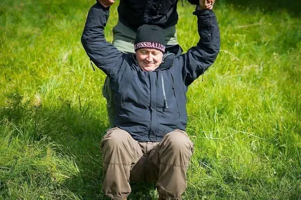 Eine Person wird von einer anderen an den Händen hochgezogen