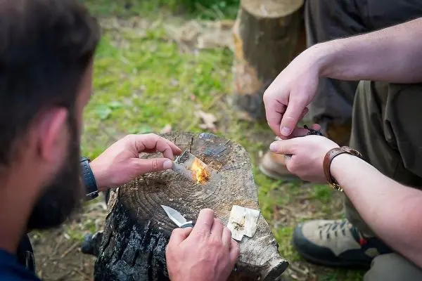 Feuerstahl erzeugt Funken auf Zunder auf einem Baumstumpf