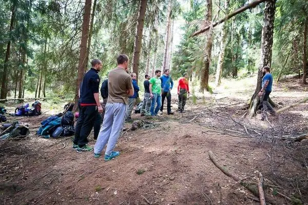 Gruppe diskutiert im Wald, Rucksäcke liegen am Boden