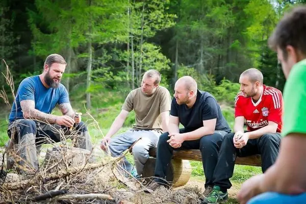 Gruppe sitzt um ein kleines Bodenfeuer und hört einem Vortrag zu