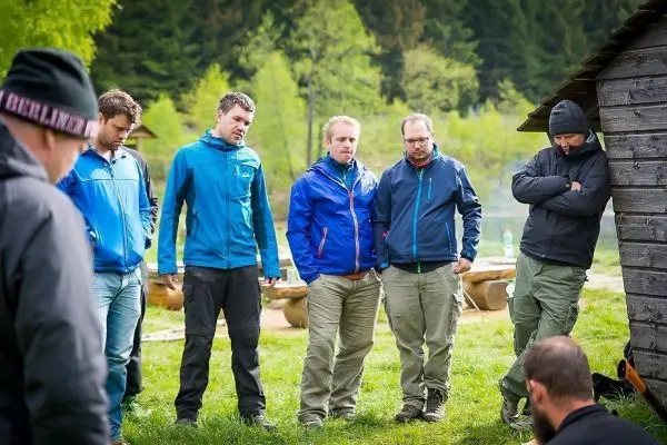 Gruppe von Personen in Outdoor-Bekleidung steht um eine Holzstruktur