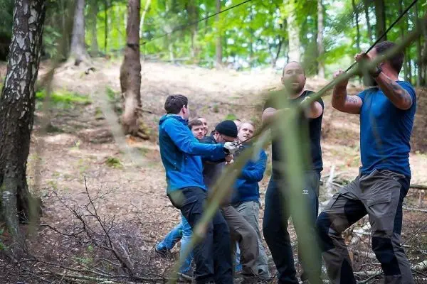 Gruppe zieht an einem Seil im Wald beim Überlebenstraining