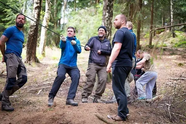 Gruppe zieht an einem Seil im Wald beim Überlebenstraining