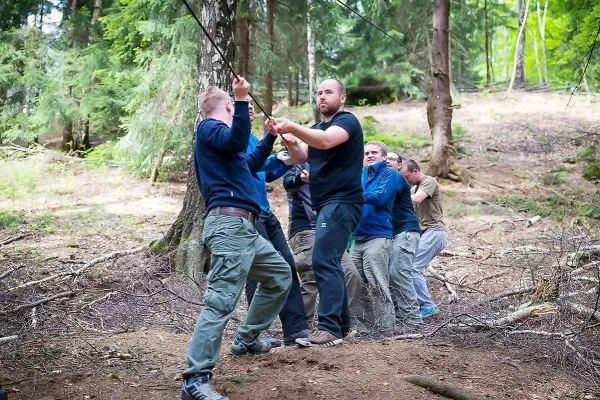 Gruppierung zieht an einem Seil in einem Waldgebiet zwischen Bäumen