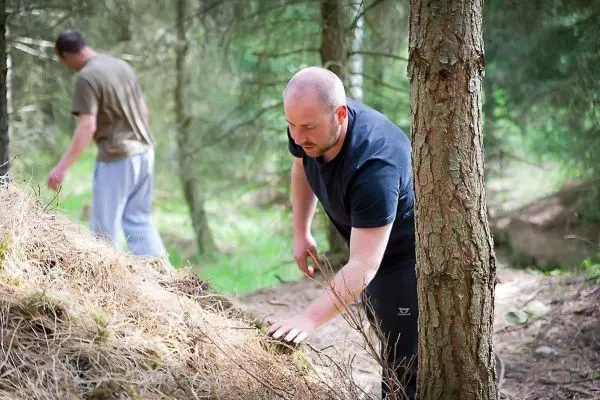 Mann bearbeitet Boden mit einer Handbewegung in einem Waldgebiet