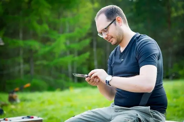 Mann bearbeitet ein Messer im Freien