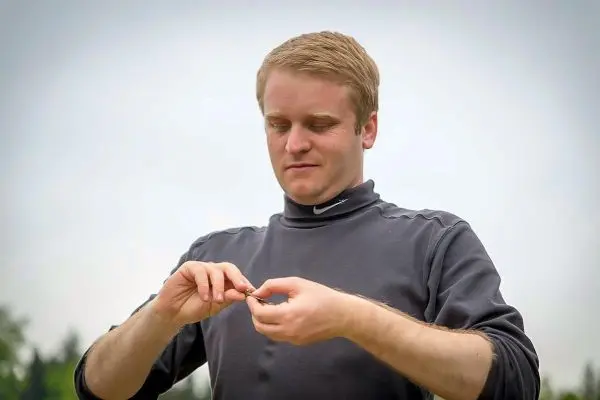 Mann hält einen kleinen Gegenstand zwischen den Fingern und konzentriert sich darauf