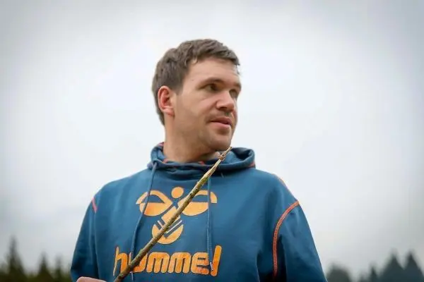 Mann hält einen Stock in der Hand und schaut nachdenklich in die Ferne