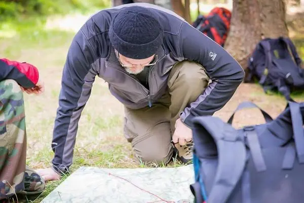 Mann kniet neben einer Karte und untersucht diese im Freien