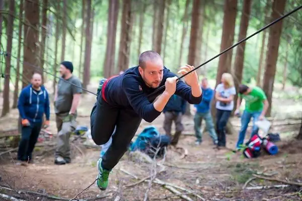Mann überquert selbstgebaute Seilbrücke zwischen Bäumen im Wald