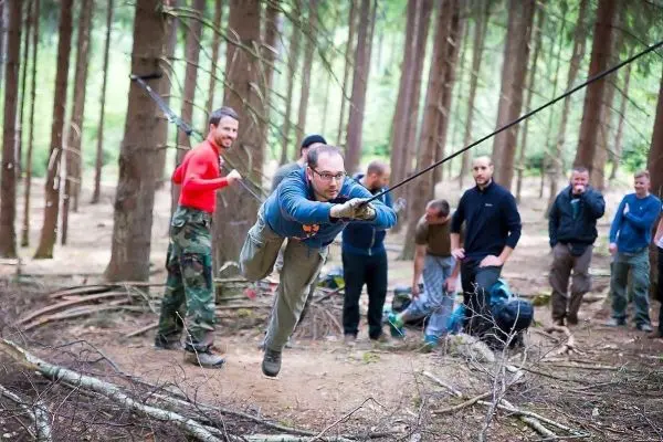 Mann überquert selbstgebaute Seilbrücke zwischen Bäumen im Wald