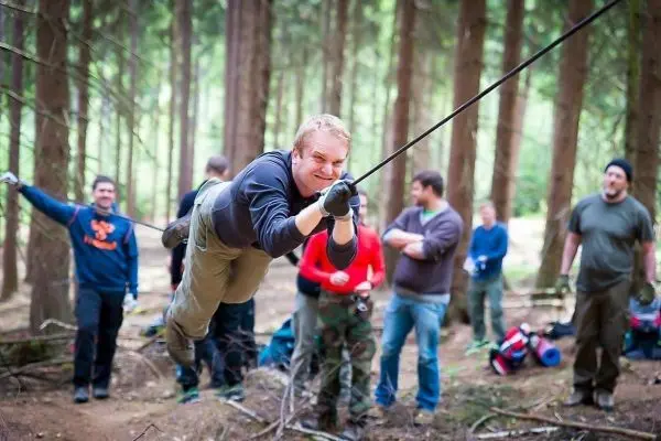 Mann überquert selbstgebaute Seilbrücke zwischen Bäumen im Wald