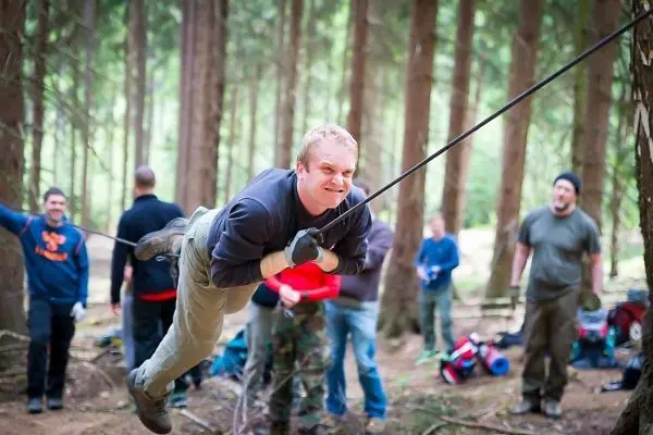 Mann überquert selbstgebaute Seilbrücke zwischen Bäumen im Wald