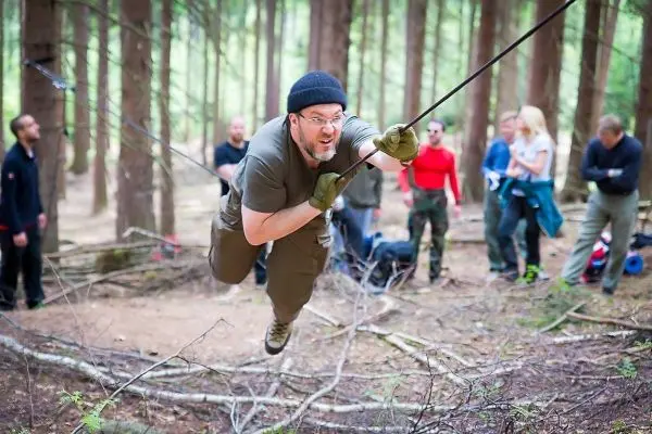 Mann überquert selbstgebaute Seilbrücke zwischen Bäumen im Wald