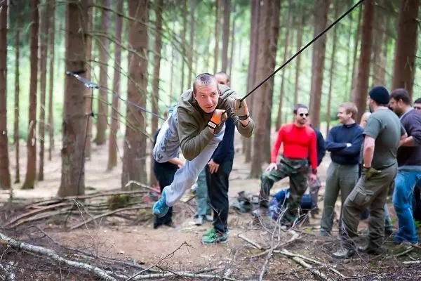 Mann überquert selbstgebaute Seilbrücke zwischen Bäumen im Wald