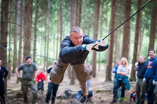 Mann überquert selbstgebaute Seilbrücke zwischen Bäumen im Wald