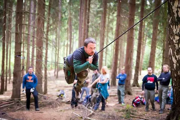 Mann überquert selbstgebaute Seilbrücke zwischen Bäumen im Wald
