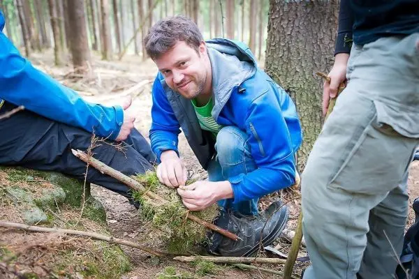 Person bindet Äste mit Moos zusammen