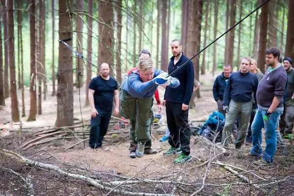 Teilnehmer überquert eine selbstgebaute Seilbrücke im Wald