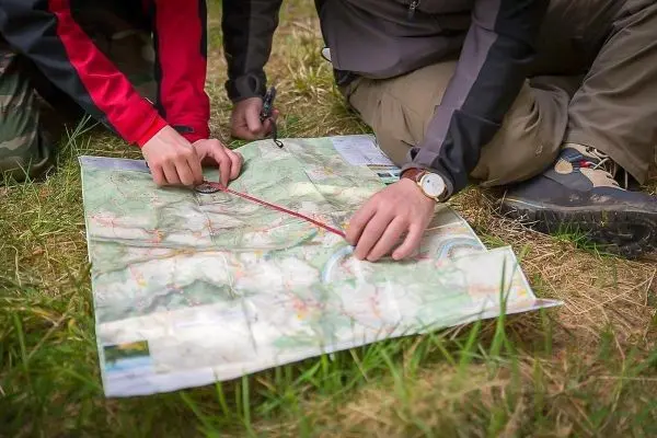 Zwei Hände legen einen Kompass auf eine Landkarte zur Orientierung
