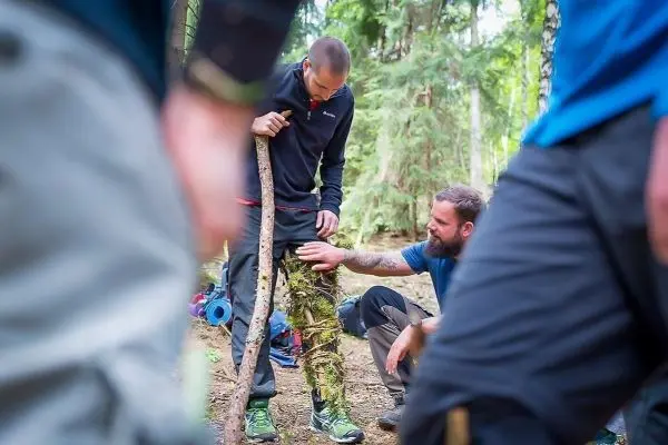 Zwei Personen arbeiten an einer improvisierten Konstruktion aus Ästen und Moos