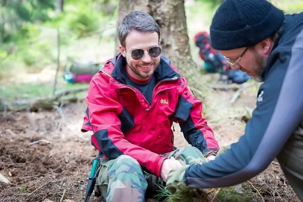 Zwei Personen arbeiten im Wald an einer Holzstruktur