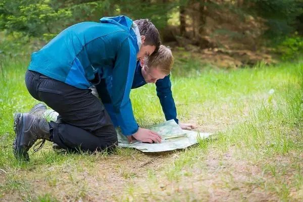 Zwei Personen betrachten gemeinsam eine Karte auf dem Boden
