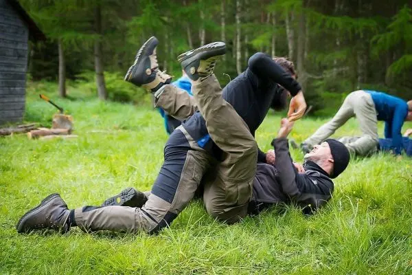 Zwei Personen im Bodenkampf auf einer Wiese, andere Teilnehmer im Hintergrund