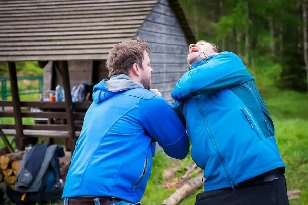 Zwei Personen in blauen Jacken üben eine körperliche Auseinandersetzung im Freien