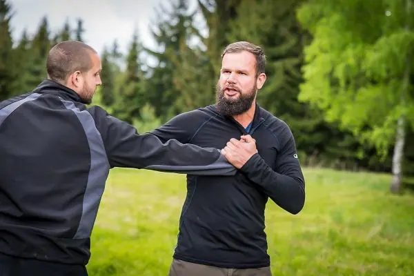 Zwei Personen in Outdoor-Bekleidung üben eine körperliche Auseinandersetzung im Freien
