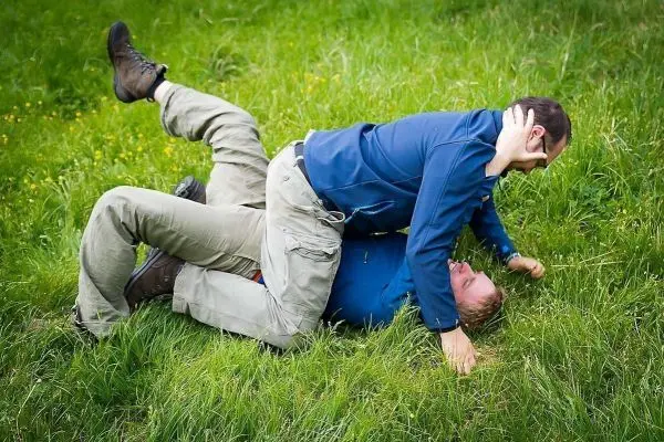 Zwei Personen liegen auf dem Gras und führen einen Bodenkampf durch