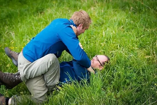 Zwei Personen ringen im hohen Gras miteinander