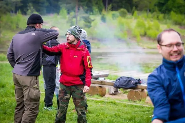 Zwei Personen stehen auf einer Wiese, eine Person berührt die andere am Arm