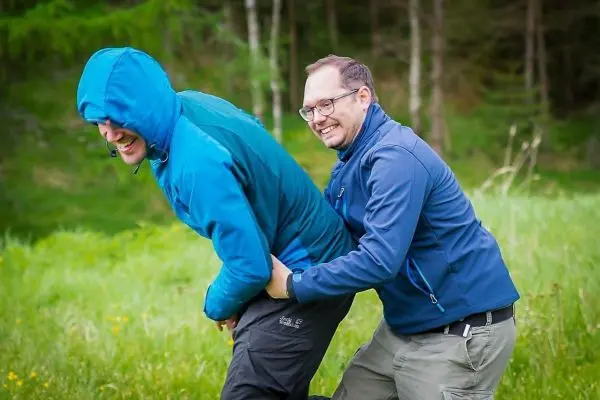 Zwei Personen stehen in einer Wiese, einer greift den anderen an