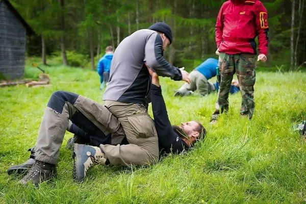 Zwei Personen üben Bodenkampftechniken auf einer Wiese